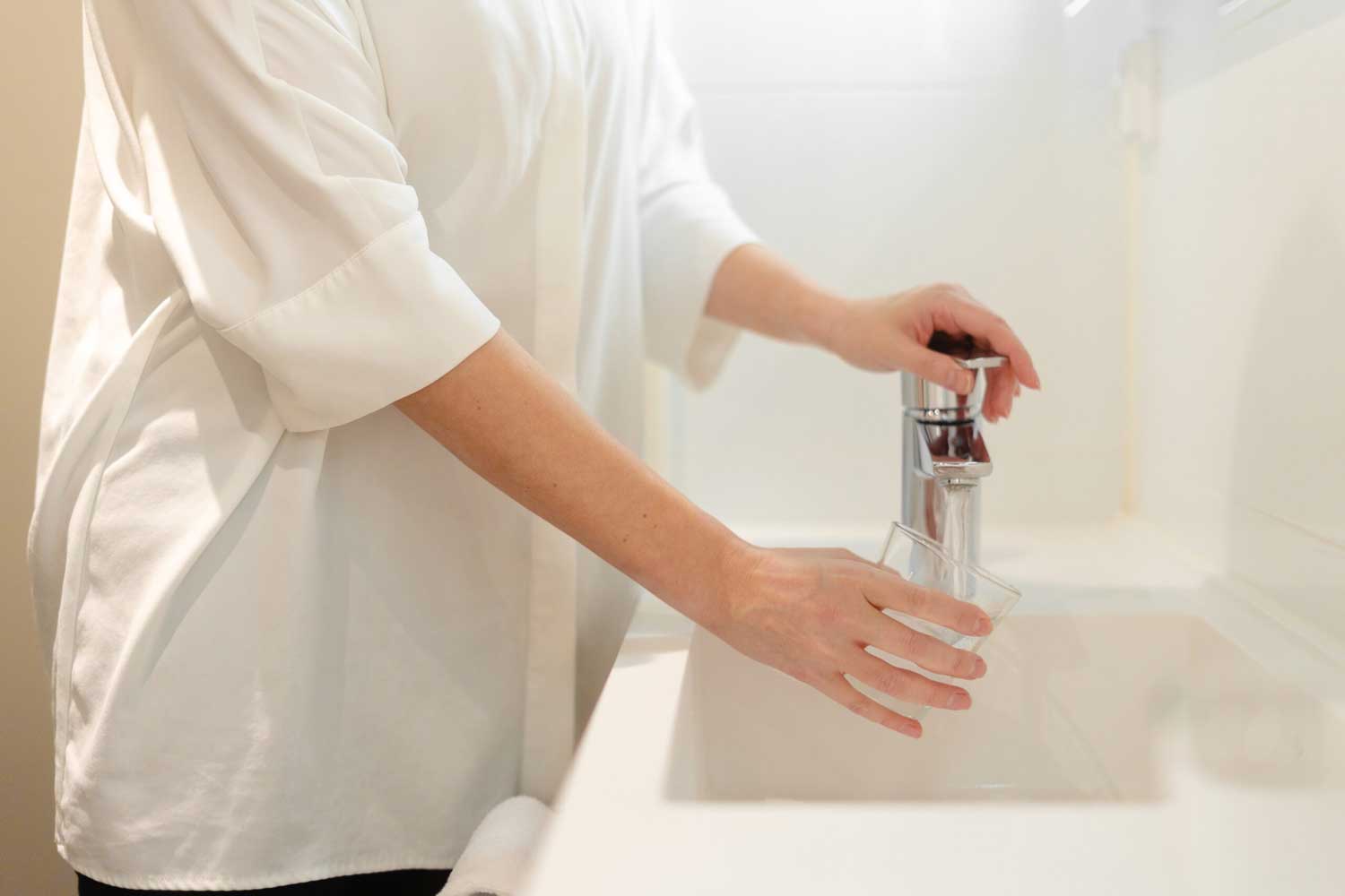 Hotellin asiakas ottaa vettä hanasta.