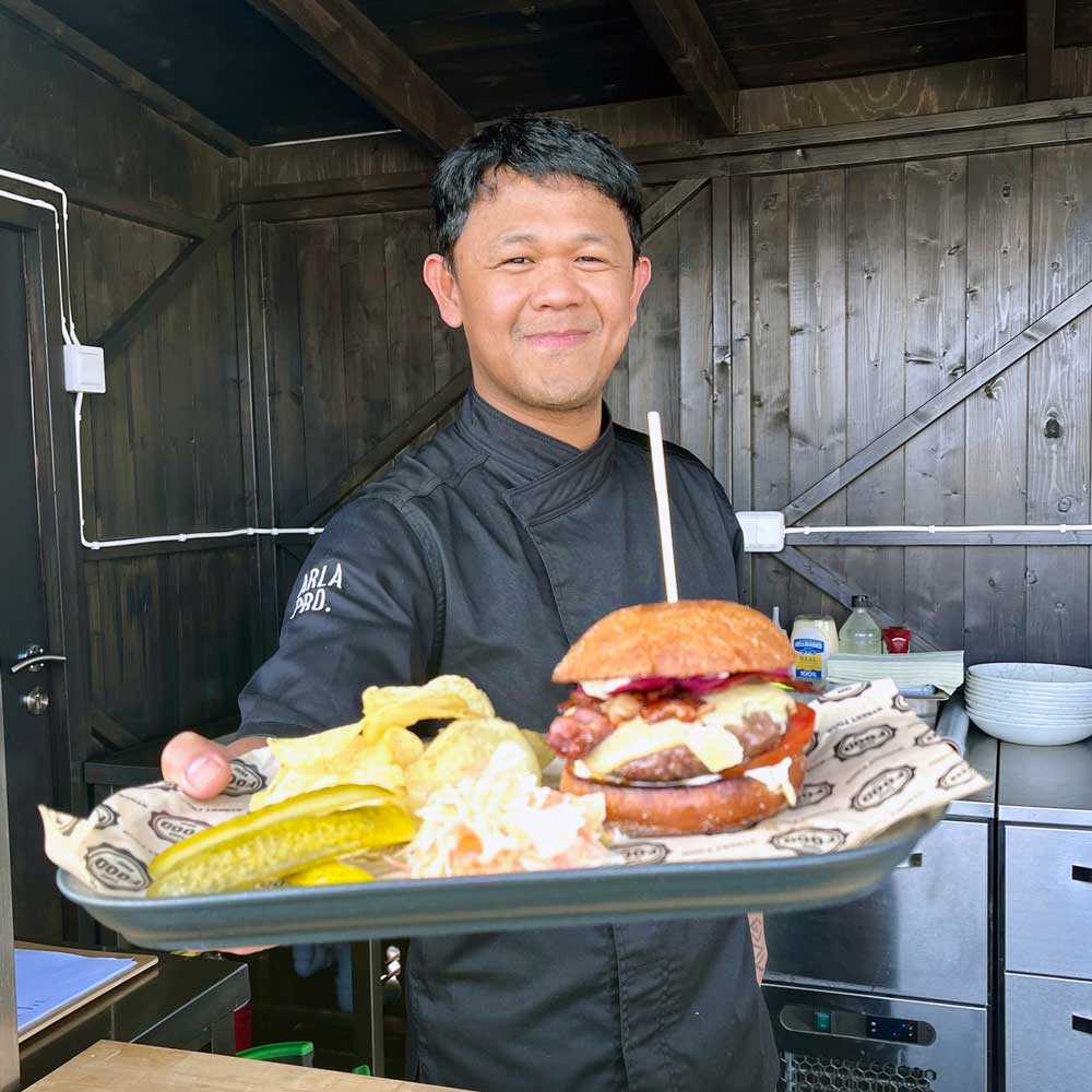 A server handing a burger from the Freja Rooftop grill.